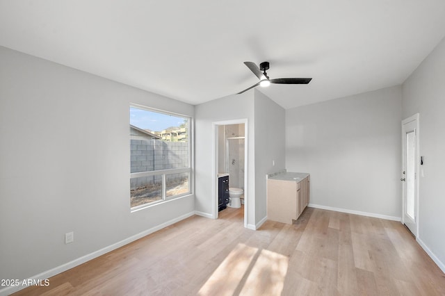interior space featuring ensuite bath, baseboards, light wood-style floors, and ceiling fan
