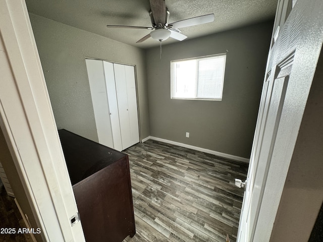 bedroom with a textured ceiling, wood finished floors, a ceiling fan, baseboards, and a closet