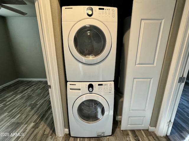 washroom featuring ceiling fan, stacked washing maching and dryer, wood finished floors, and baseboards