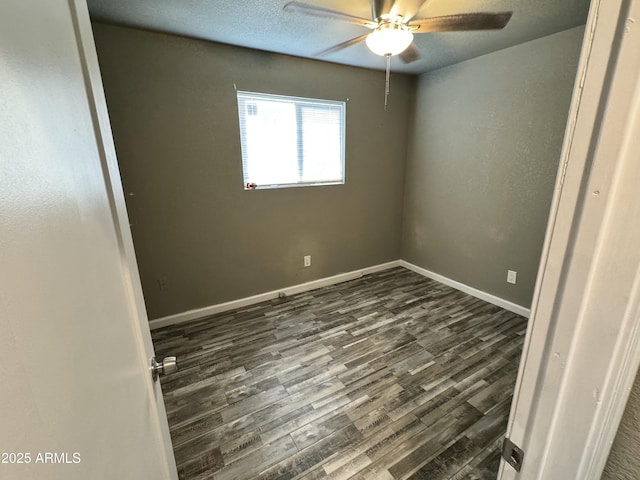 spare room with a ceiling fan, baseboards, and dark wood-type flooring