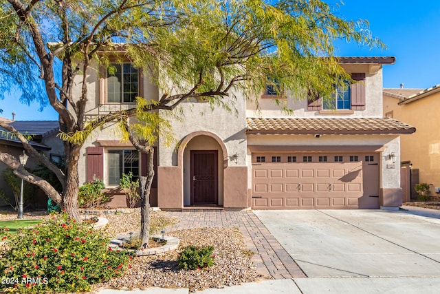 mediterranean / spanish-style home featuring a tiled roof, driveway, stucco siding, and an attached garage