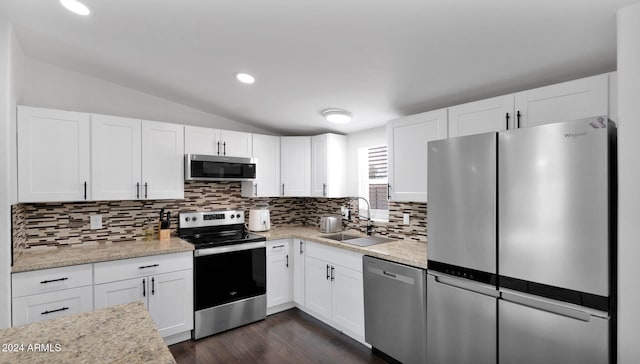 kitchen with sink, light stone counters, lofted ceiling, white cabinets, and appliances with stainless steel finishes