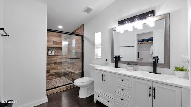 bathroom with hardwood / wood-style flooring, vanity, a shower with shower door, and toilet