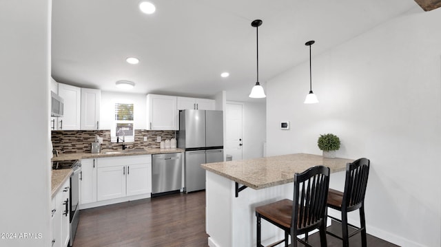 kitchen featuring a kitchen breakfast bar, white cabinetry, hanging light fixtures, and appliances with stainless steel finishes