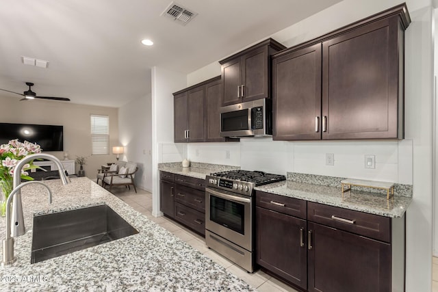 kitchen featuring stainless steel appliances, a sink, visible vents, open floor plan, and dark brown cabinets