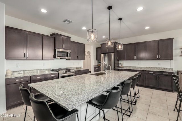 kitchen featuring stainless steel appliances, a sink, visible vents, and dark brown cabinetry