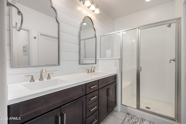 full bath featuring tile patterned floors, a sink, a shower stall, and double vanity