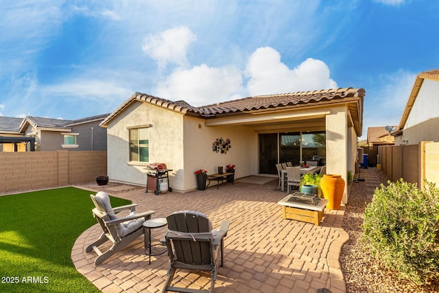 back of house featuring a tile roof, stucco siding, a lawn, a patio area, and a fenced backyard