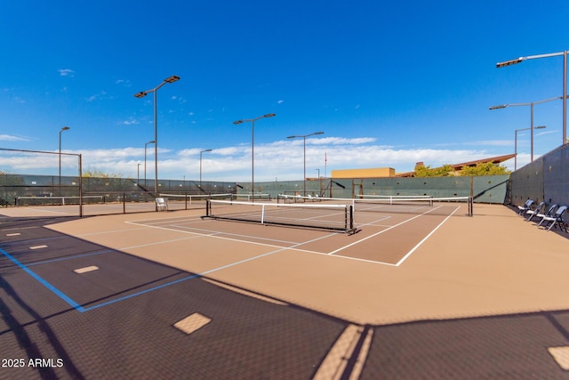 view of tennis court featuring community basketball court and fence