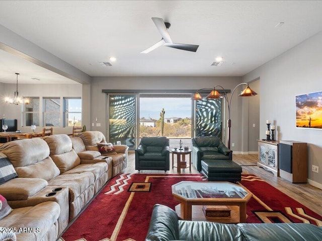 living room featuring ceiling fan with notable chandelier and wood-type flooring