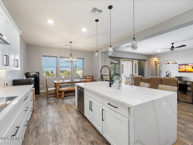 kitchen featuring white cabinetry, sink, a kitchen island with sink, and hanging light fixtures