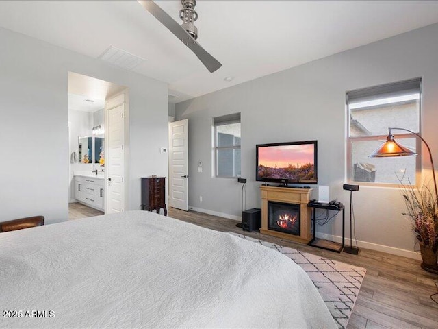 bedroom featuring connected bathroom, light hardwood / wood-style flooring, and ceiling fan