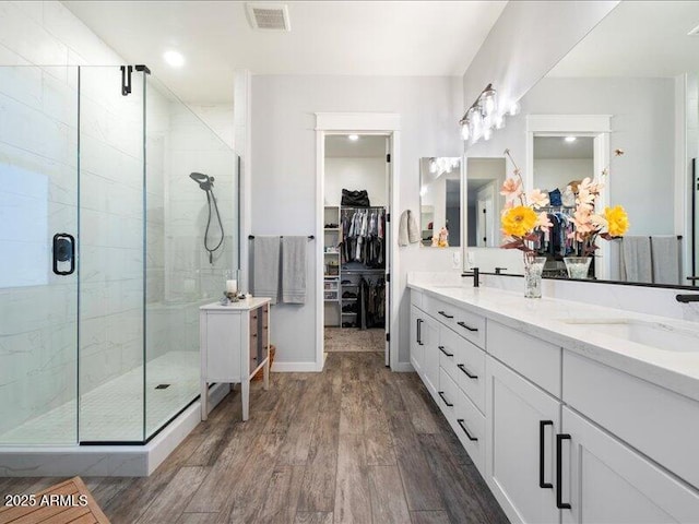 bathroom featuring an enclosed shower, vanity, and wood-type flooring