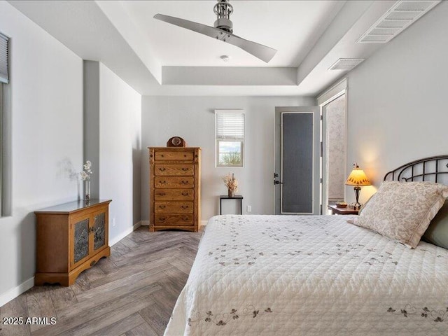 bedroom with ceiling fan, parquet flooring, and a raised ceiling