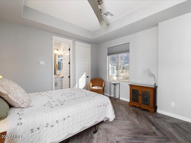 bedroom featuring connected bathroom, a tray ceiling, and dark parquet floors