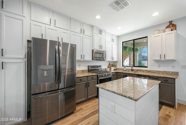 18841 E Pelican Ct, Queen Creek, AZ 85142 - kitchen featuring light stone counters, visible vents, a sink, stainless steel appliances, and light wood-type flooring