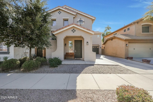 mediterranean / spanish home with a tiled roof, a garage, driveway, and stucco siding