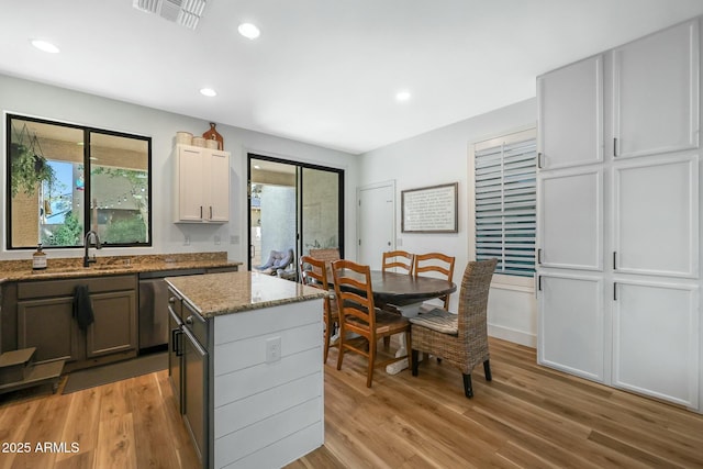 18841 E Pelican Ct, Queen Creek, AZ 85142 - kitchen featuring light wood finished floors, visible vents, a kitchen island, dishwasher, and a sink