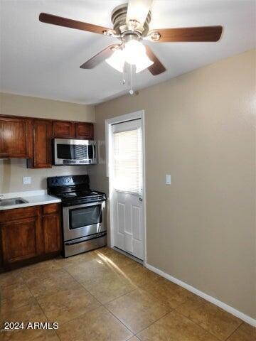 kitchen featuring appliances with stainless steel finishes, light tile patterned floors, sink, and ceiling fan