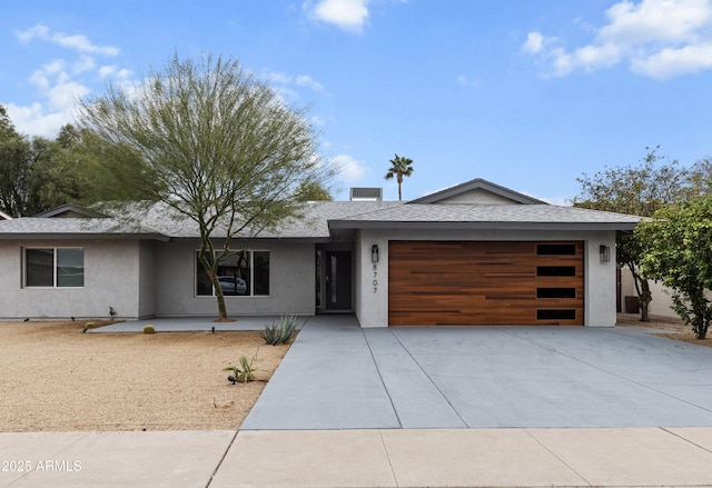 view of front facade with an attached garage, concrete driveway, and stucco siding