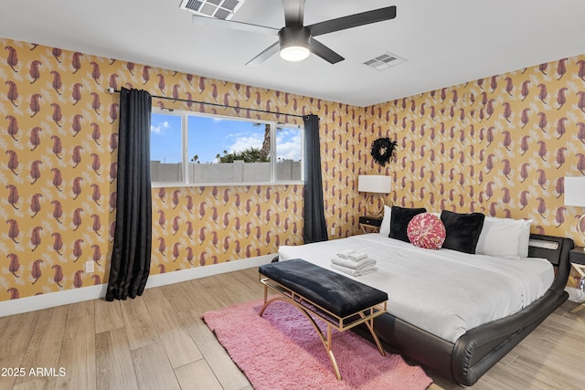 bedroom featuring wood finished floors, wallpapered walls, ceiling fan, baseboards, and visible vents