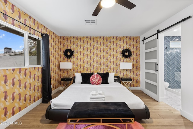 bedroom with wallpapered walls, visible vents, and a barn door
