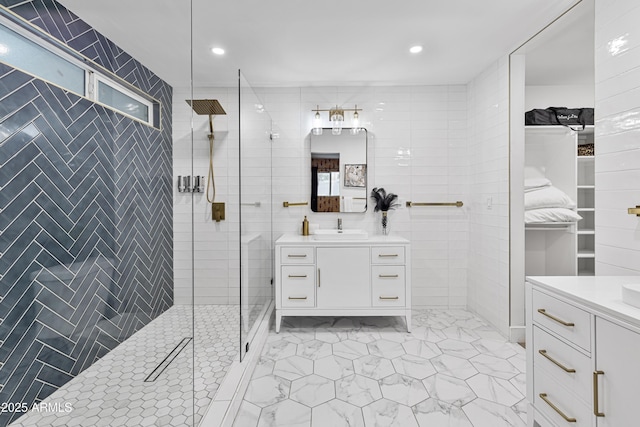 bathroom featuring vanity, a spacious closet, marble finish floor, and a stall shower