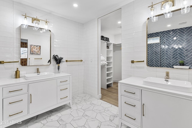 full bath with two vanities, a sink, and tile walls