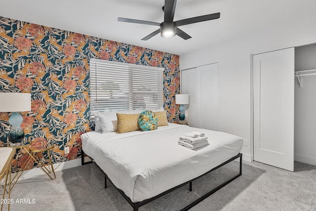 bedroom with wallpapered walls, multiple closets, a ceiling fan, carpet floors, and baseboards