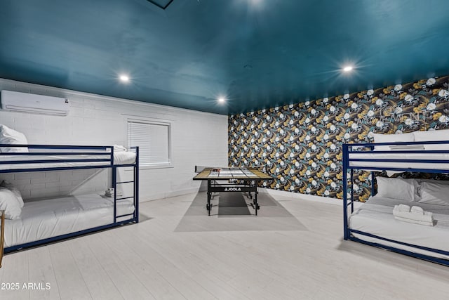 bedroom with a wall mounted air conditioner, baseboards, wood finished floors, and recessed lighting