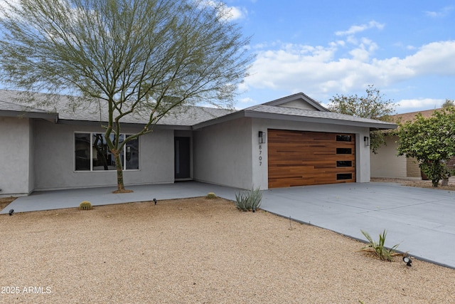 view of front of property with an attached garage, a shingled roof, stucco siding, and driveway