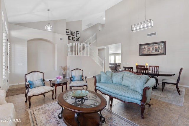 living area featuring high vaulted ceiling, visible vents, baseboards, and stairs