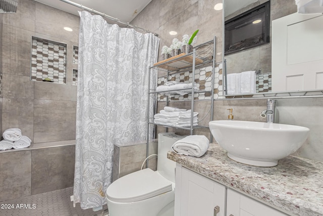 bathroom with vanity, toilet, and tile walls