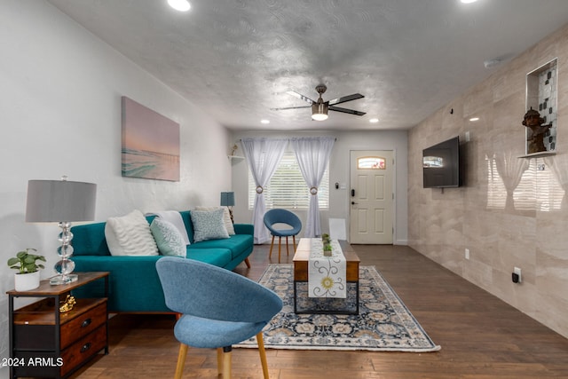 living room featuring tile walls, a textured ceiling, dark wood-type flooring, and ceiling fan