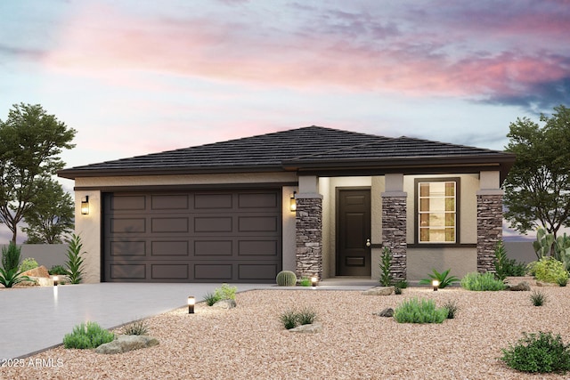 prairie-style house with a garage, stucco siding, driveway, and stone siding