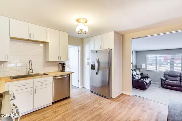 2723 Towell St, Overgaard, AZ 85933 - kitchen with appliances with stainless steel finishes, a sink, white cabinetry, light wood-type flooring, and backsplash