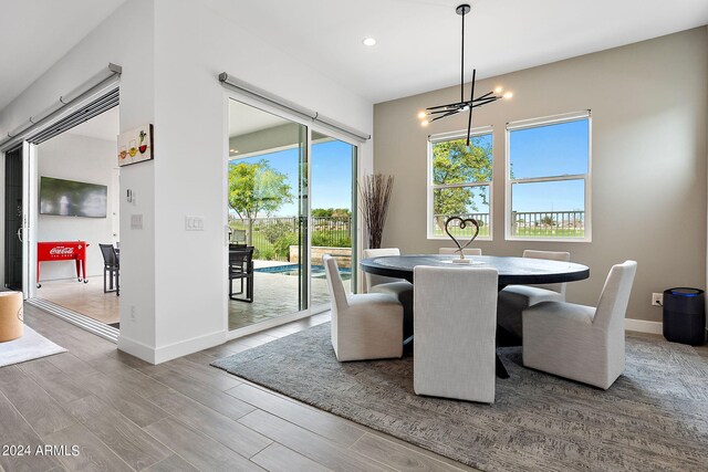 dining area with a healthy amount of sunlight, light hardwood / wood-style floors, and an inviting chandelier