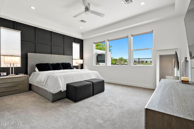 carpeted bedroom featuring ceiling fan and a raised ceiling