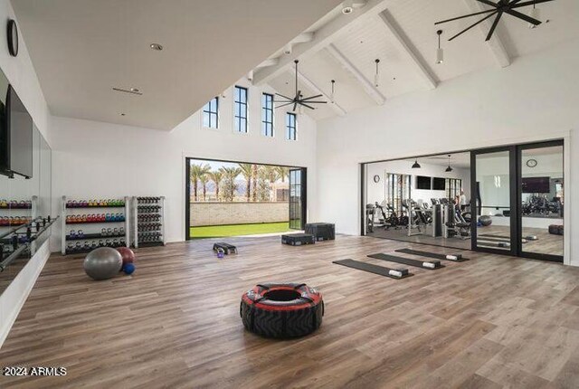 gym with high vaulted ceiling, dark wood-type flooring, and ceiling fan