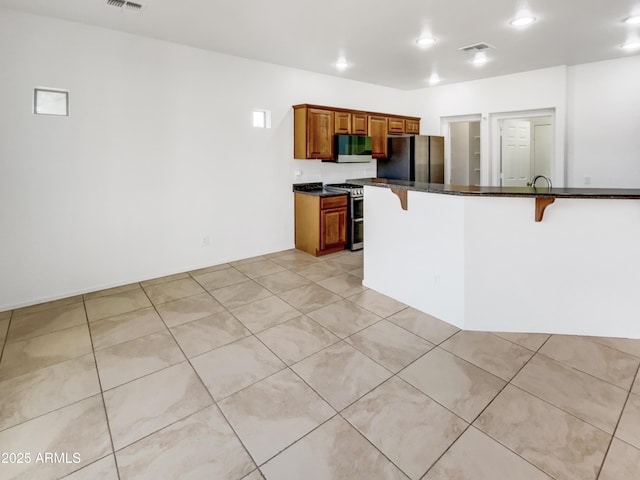 kitchen with stainless steel appliances, a kitchen breakfast bar, kitchen peninsula, and light tile patterned flooring