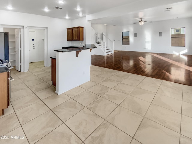 kitchen featuring light tile patterned flooring, ceiling fan, and a kitchen bar