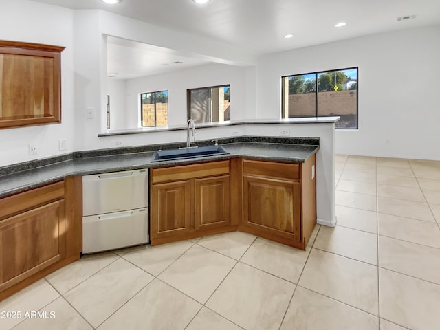 kitchen featuring light tile patterned flooring, dark stone countertops, sink, and stainless steel dishwasher