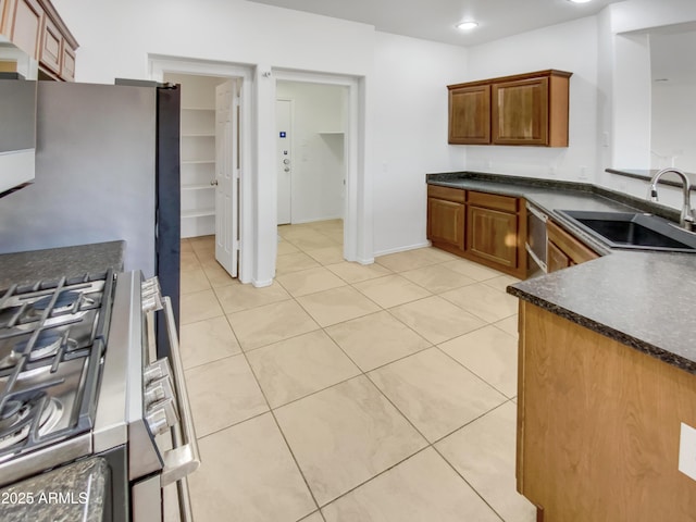 kitchen featuring stainless steel gas range, sink, and light tile patterned floors