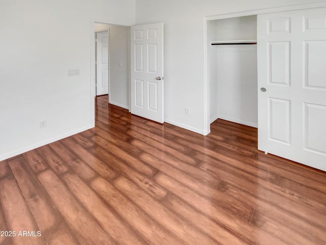 unfurnished bedroom with dark hardwood / wood-style flooring and a closet