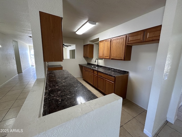 3814 N 55th Dr, Phoenix, AZ 85031 - kitchen with a sink, light tile patterned floors, brown cabinets, dark stone countertops, and a ceiling fan