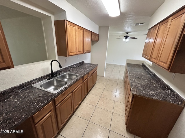 3814 N 55th Dr, Phoenix, AZ 85031 - kitchen with a sink, a ceiling fan, light tile patterned floors, brown cabinetry, and dark stone counters