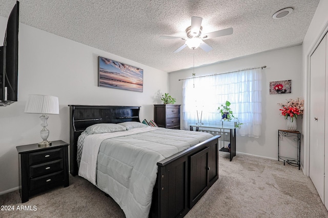 carpeted bedroom featuring ceiling fan, a textured ceiling, and a closet