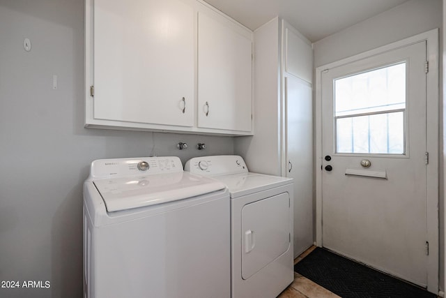 clothes washing area with cabinets, light tile patterned flooring, and washer and dryer