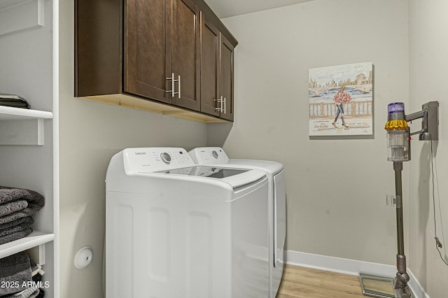 washroom featuring cabinets, separate washer and dryer, and light hardwood / wood-style floors