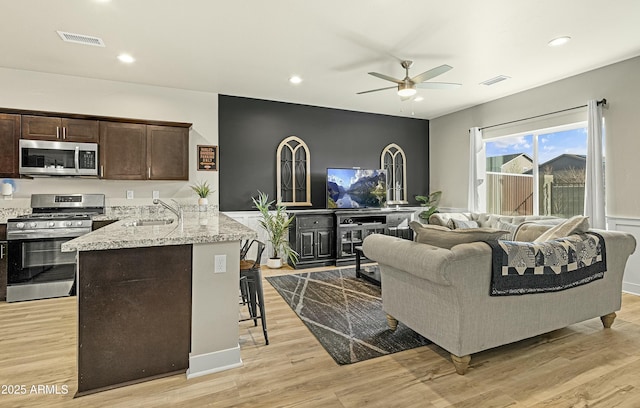 living room featuring ceiling fan, sink, and light wood-type flooring